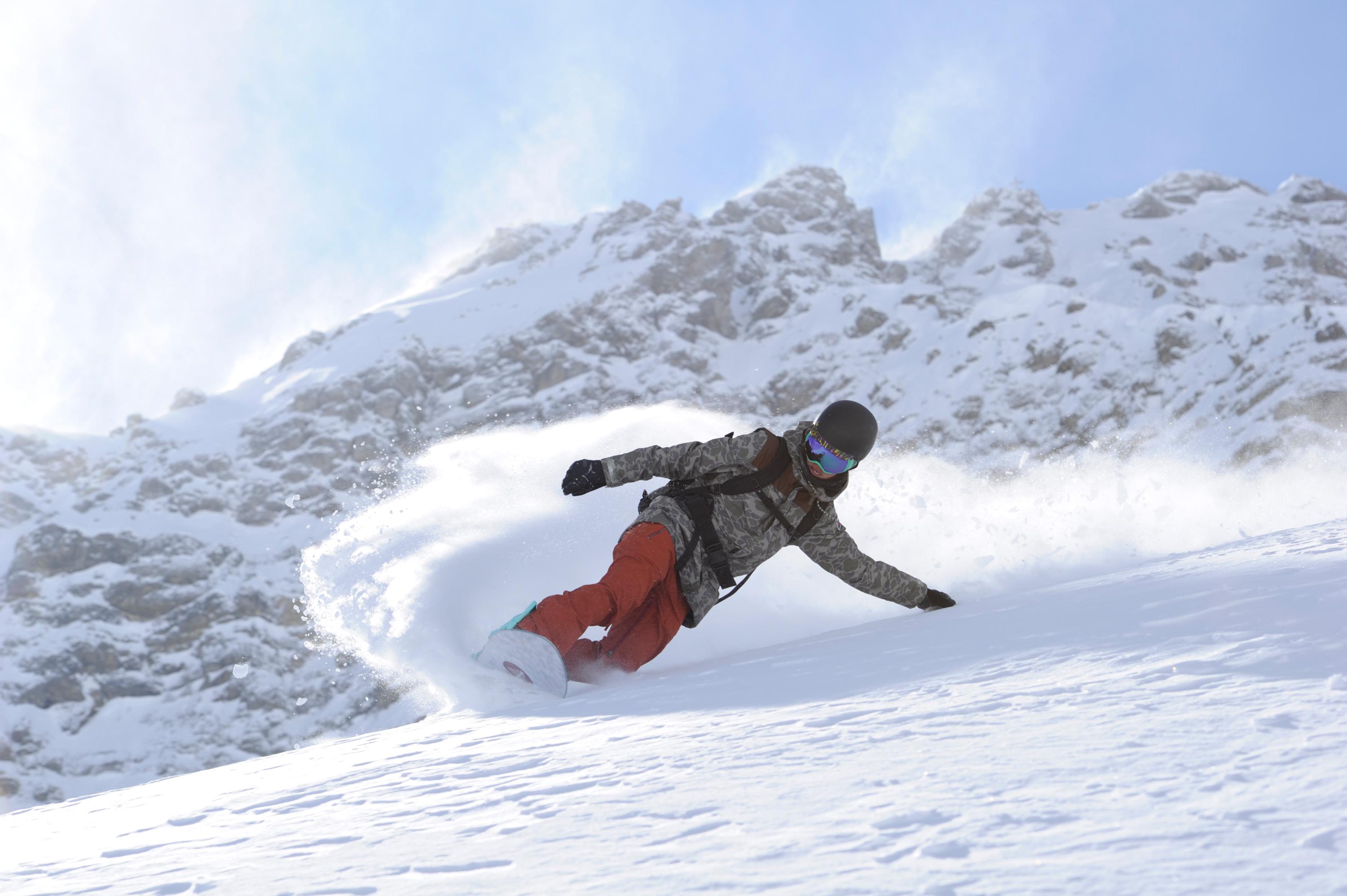 Ein Snowboarder f&auml;hrt im Tiefschnee durchs Gel&auml;nde.