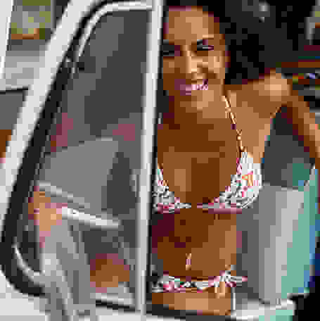 Eine Frau steigt in einem Bikini aus dem Auto.