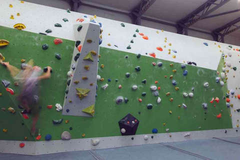 Eine Frau bouldert horizontal eine Kletterwand entlang Fotostrecke Bild 1