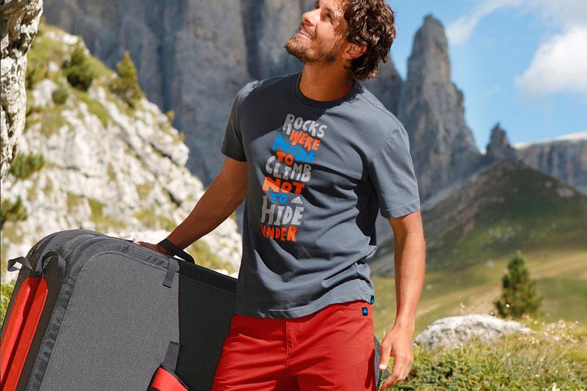 Ein Mann steht in eine sonnigen alpinen Landschaft mit seiner Bouldermatte