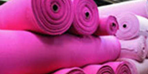 Große Stoffrollen zur Fertigung von Kleidung sind zu Türmen aufgeschichtet.