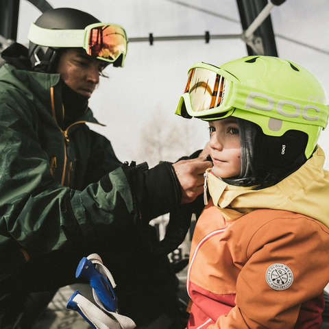 Ein Vater und sein Kind bereiten sich in der Gondel zum Skifahren vor.