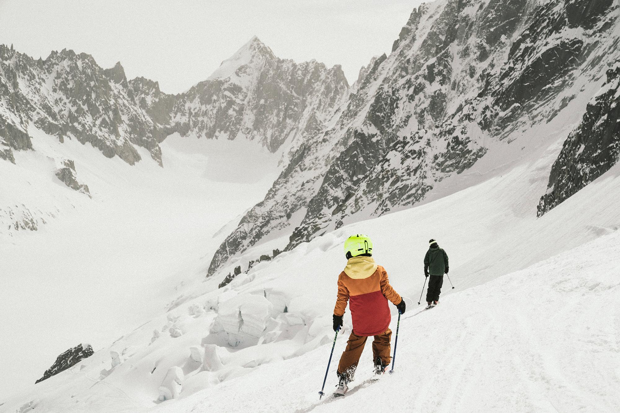 Ein Kind und ein Erwachsener Skifahrer fahren auf Ski eine anspruchsvolle Piste hinab.