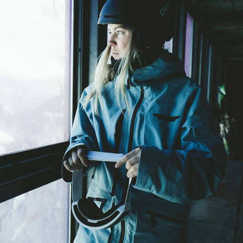 Eine Frau in voller Skitourenbekleidung in einer Hütte kurz vor der Abfahrt 