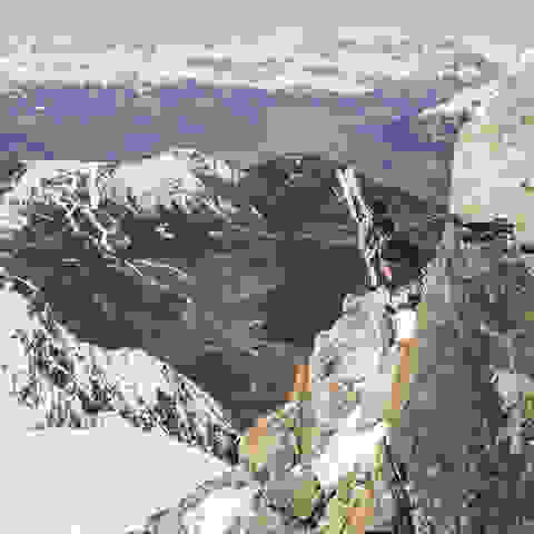 Eine Bergkette, auf der sich eine Skitourengeherin abseilt. 