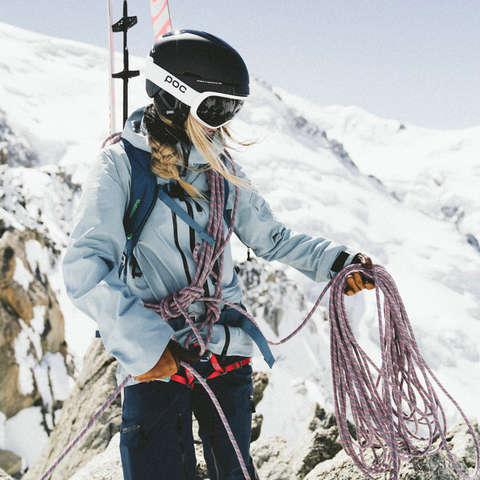 Eine Skitourerin die voll ausgerüstet ist. Sie tragt Skier, Rucksack,Helm. Seil und vieles mehr. 