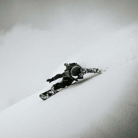 Ein Snowboarder fährt eine Piste hinab. Sein Fahrniveau ist sehr hoch.