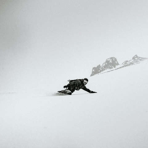 Ein Snowboarder fährt abseits der Piste einen unberührten Tiefschneehang hinab.