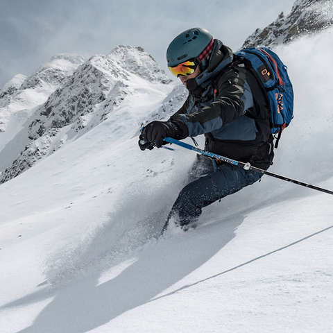 Ein Freeride Skifahrer fährt mit seinen Freeride Ski einen Hang im Tiefschnee hinab