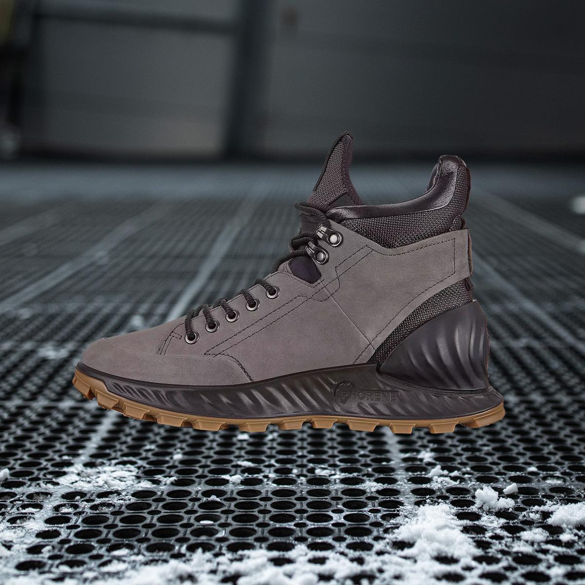 Ein brauner Wintersneaker auf einem verschneiten Gitter