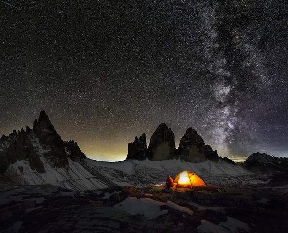 Ein Zelt steht in der Nacht vor den Drei Zinnen in den Dolomiten.