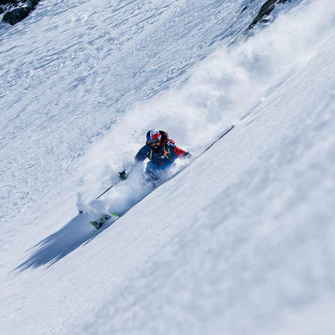 Ein Skifahrer fahrt im Pulverschnee die Piste hinab.