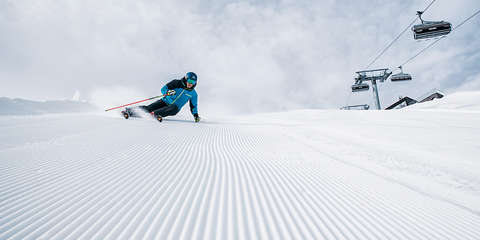 Ein Skifahrer fährt sehr schnell eine präparierte Piste hinab.