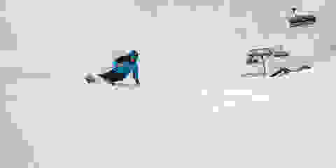 Ein Skifahrer fährt sehr schnell eine präparierte Piste hinab.