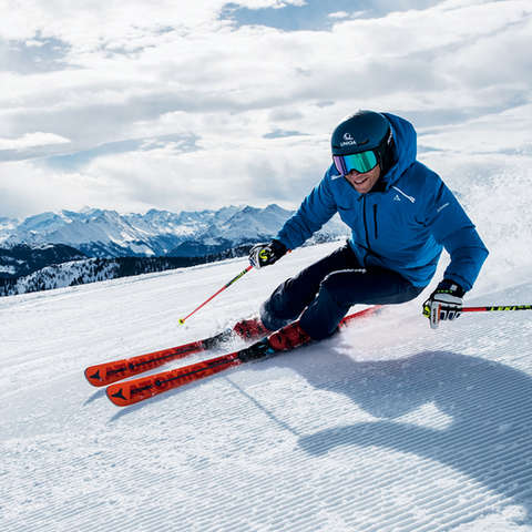 Ein Skifahrer fährt mit Skistöcken in der Hand eine Piste im Carving Schwung hinab