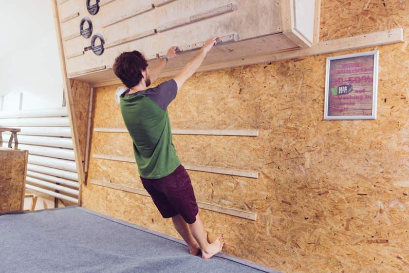 Ein Mann trainiert am Campusboard im stehen.