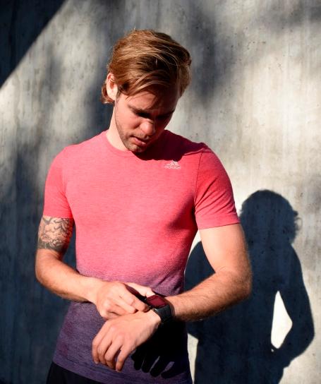 Ein Mann trägt einen Fitness Tracker am linken Handgelenk und nimmt eine Einstellung vor.