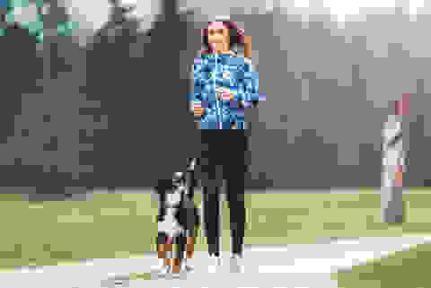 Eine junge Frau joggt mit einem jungen Hund
