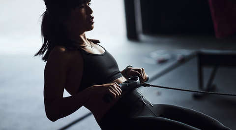 Eine Frau am Rudergerät in einem Crossfitstudio um ihre Kondition zu verbessern.