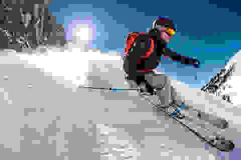 Eine Frau ist auf Freeride Skiern unterwegs im Tiefschnee.