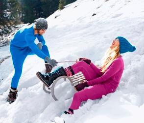 Ein Mann und eine Frau spielen im Schnee in Merinowolle Unterwäsche.