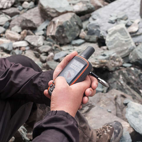 Ein GPS-Gerät dient einem mann beim Geocaching zur Orientierung.