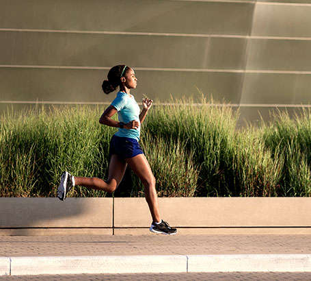 Eine Frau läuft während der Trainingsanalyse an einem Gebäude auf der Straße entlang.
