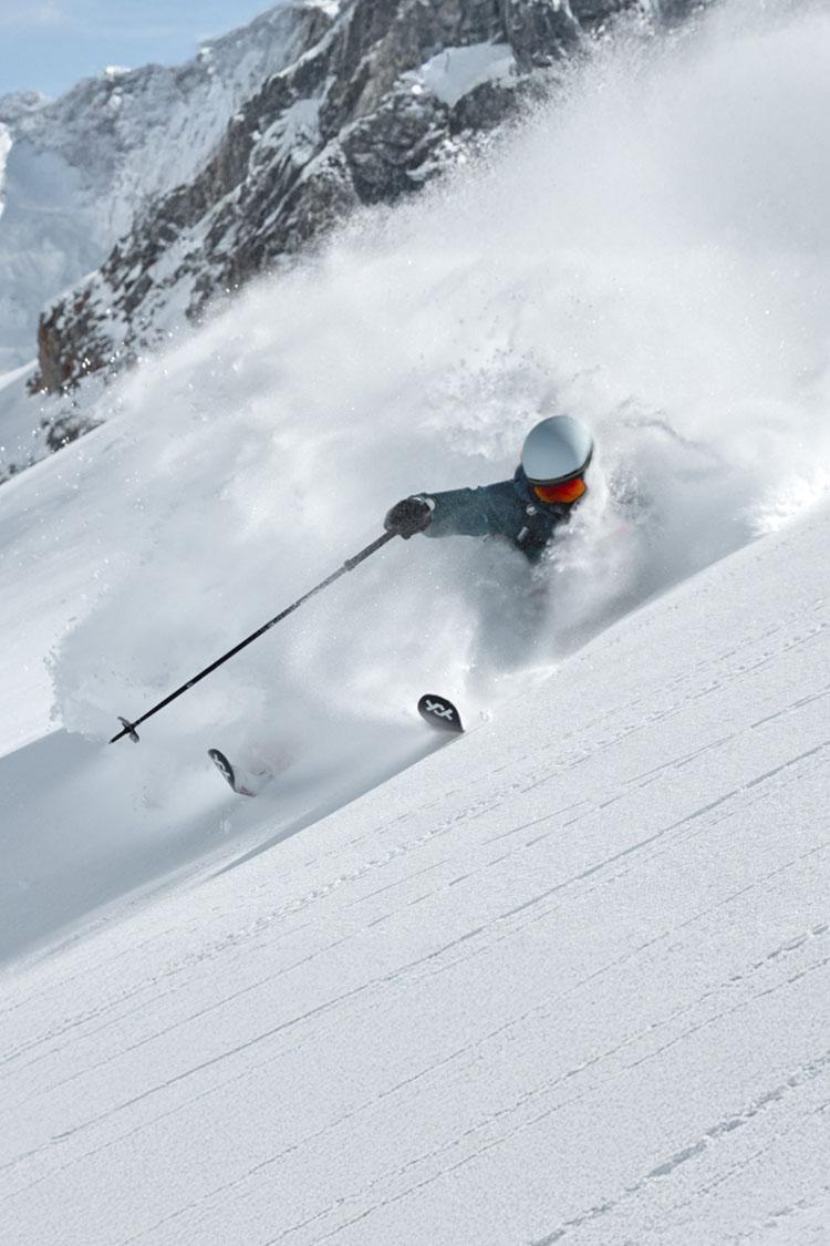Ein Skifahrer macht eine Bergabfahrt in einer alpinen Schneelandschaft