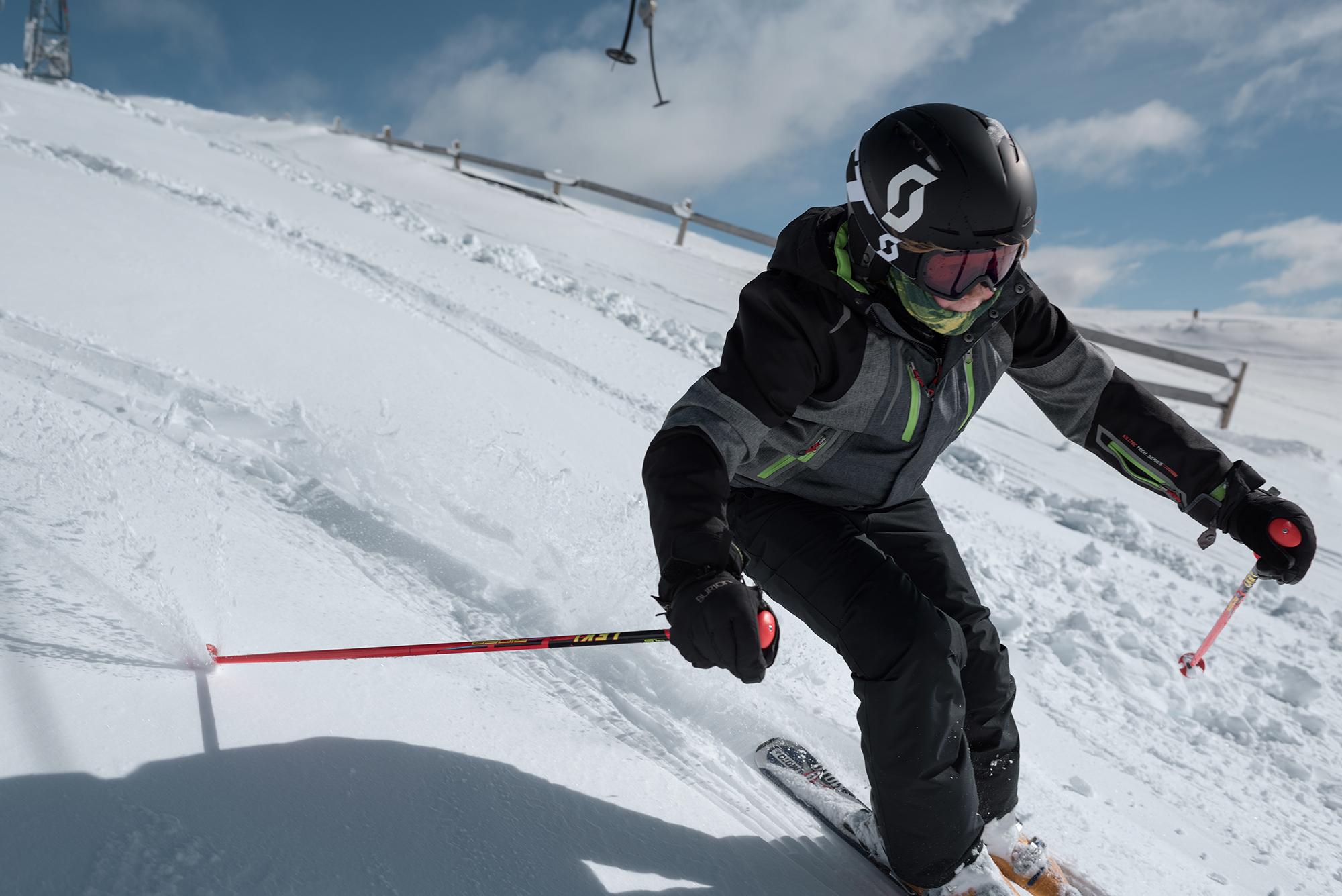 Ein Kind f&auml;hrt mit Skist&ouml;cken in der Hand durch einen flachen Tiefschneehang