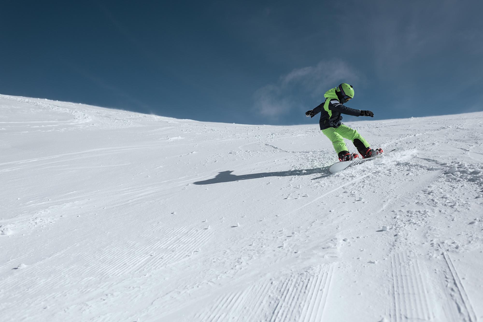 Ein sehr junger Snowboarder f&auml;hrt eine Piste hinunter