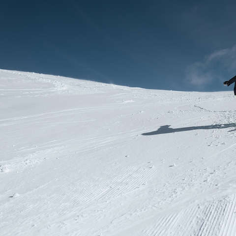 Ein sehr junger Snowboarder fährt eine Piste hinunter.