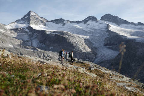 Ein Mann und eine Frau wandern vor einem Gletscher-Massiv