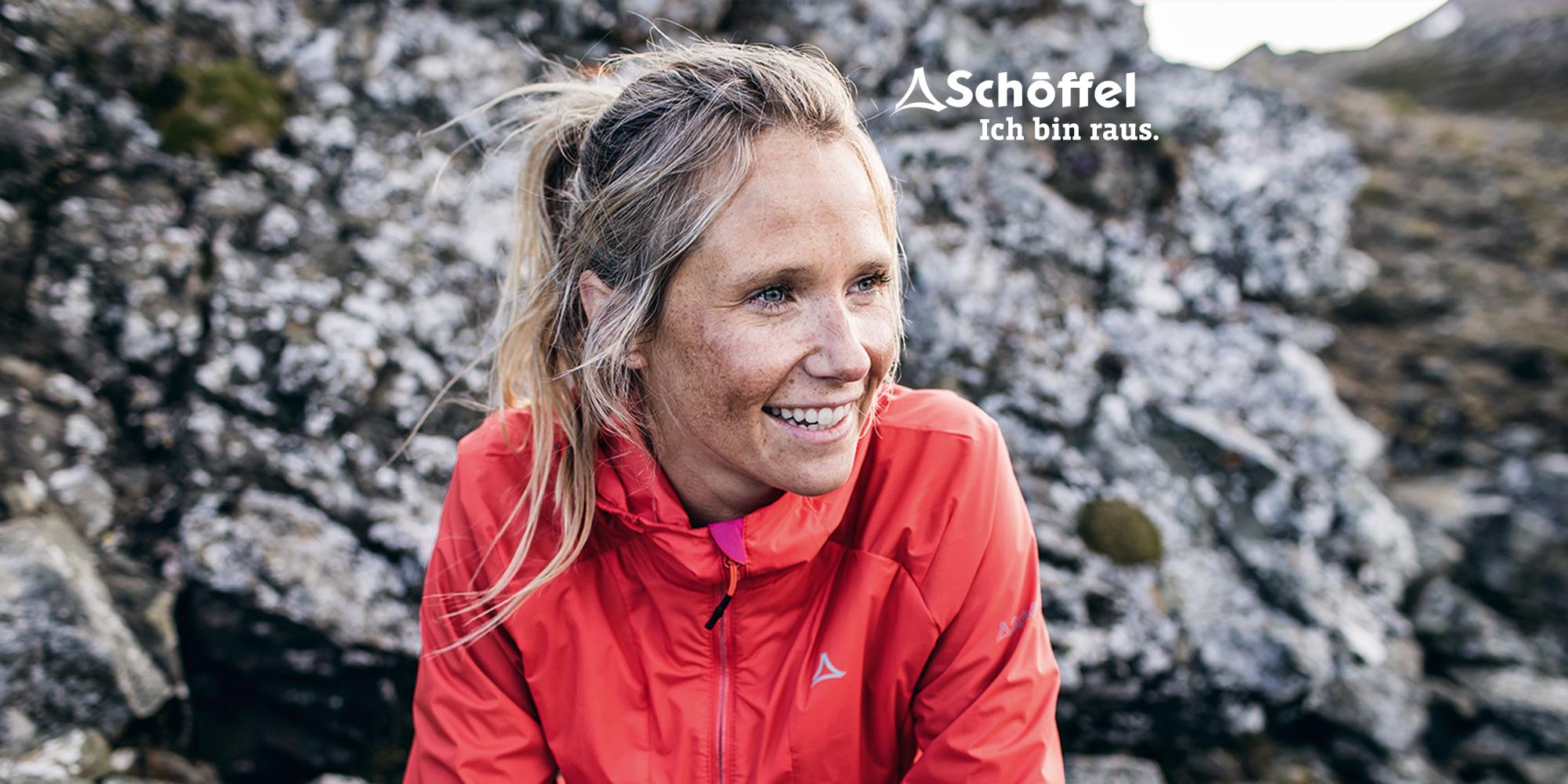 Eine Frau lacht in die Kamera und tr&auml;gt dabei eine rote Sch&ouml;ffel ZipIn! Jacke