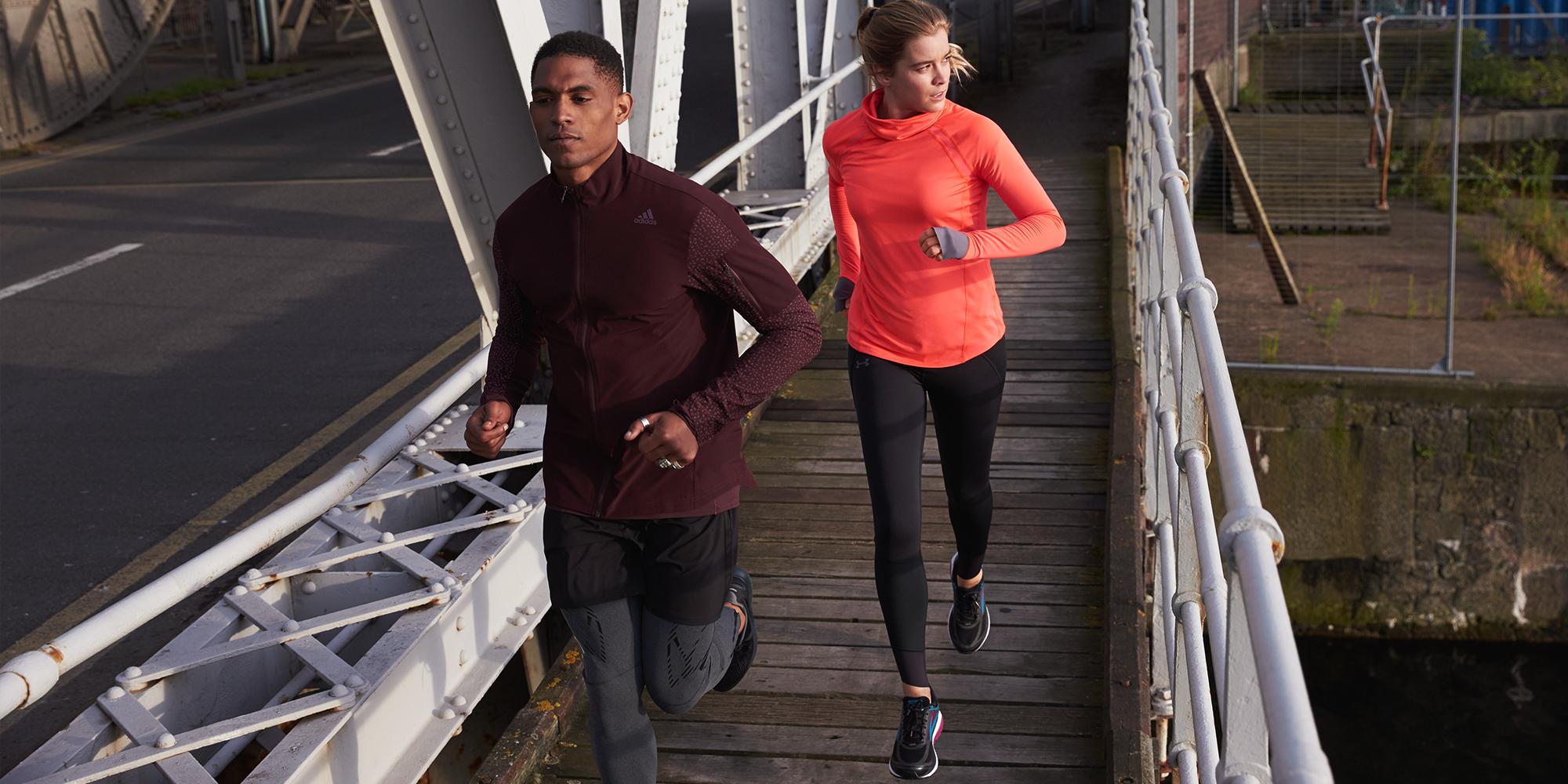 Eine Frau und ein Mann beim lockeren Joggen am Abend auf einer Brücke.