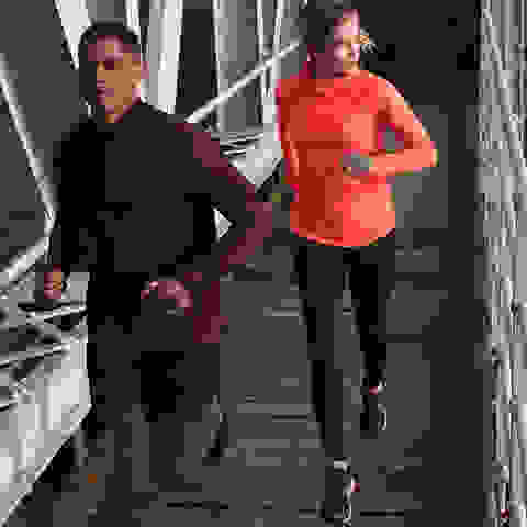 Eine Frau und ein Mann beim lockeren Joggen am Abend auf einer Brücke.