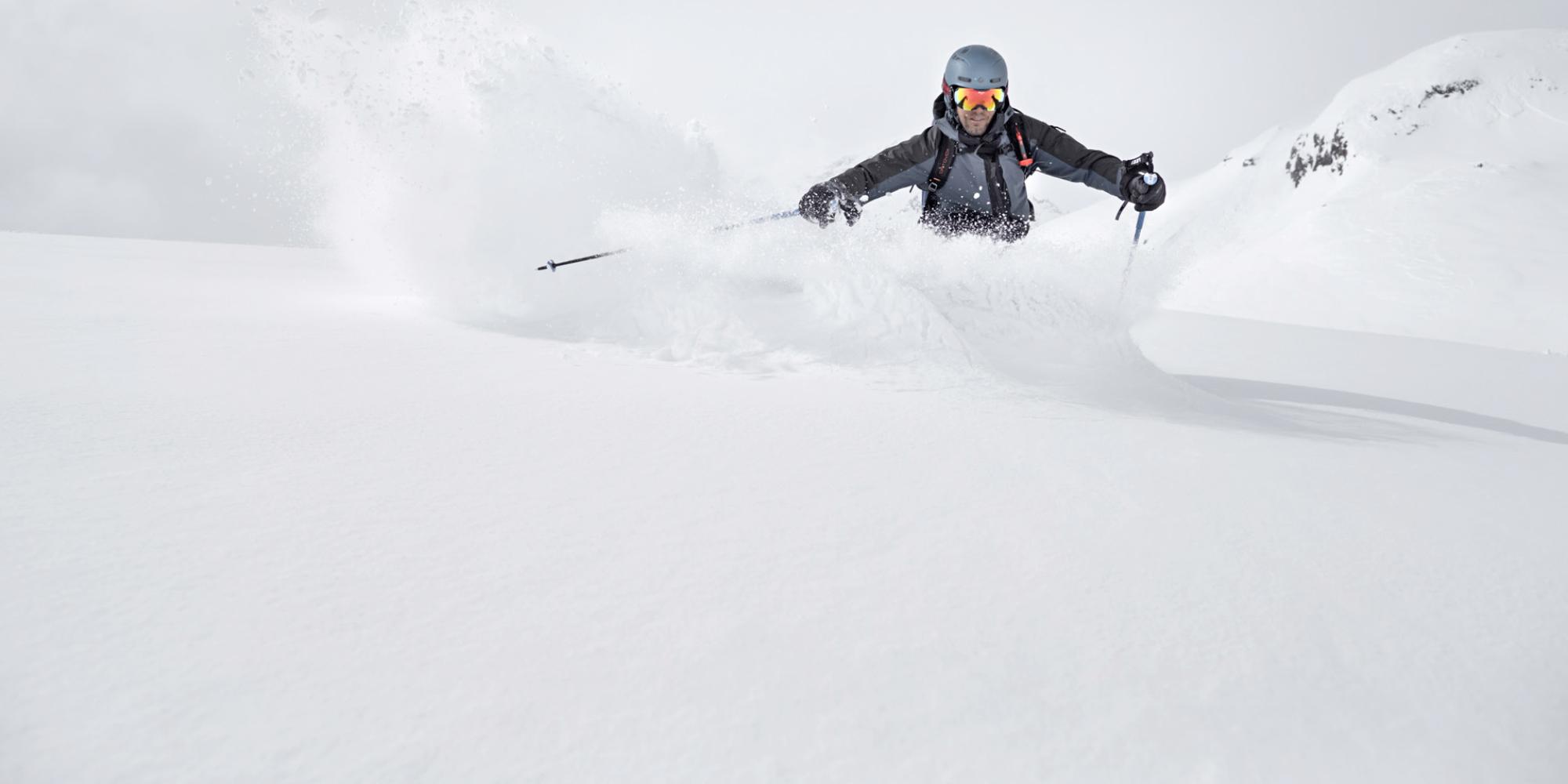 Ein Skifahrer macht eine Pistenabfahrt in einer verschneiten Berglandschaft
