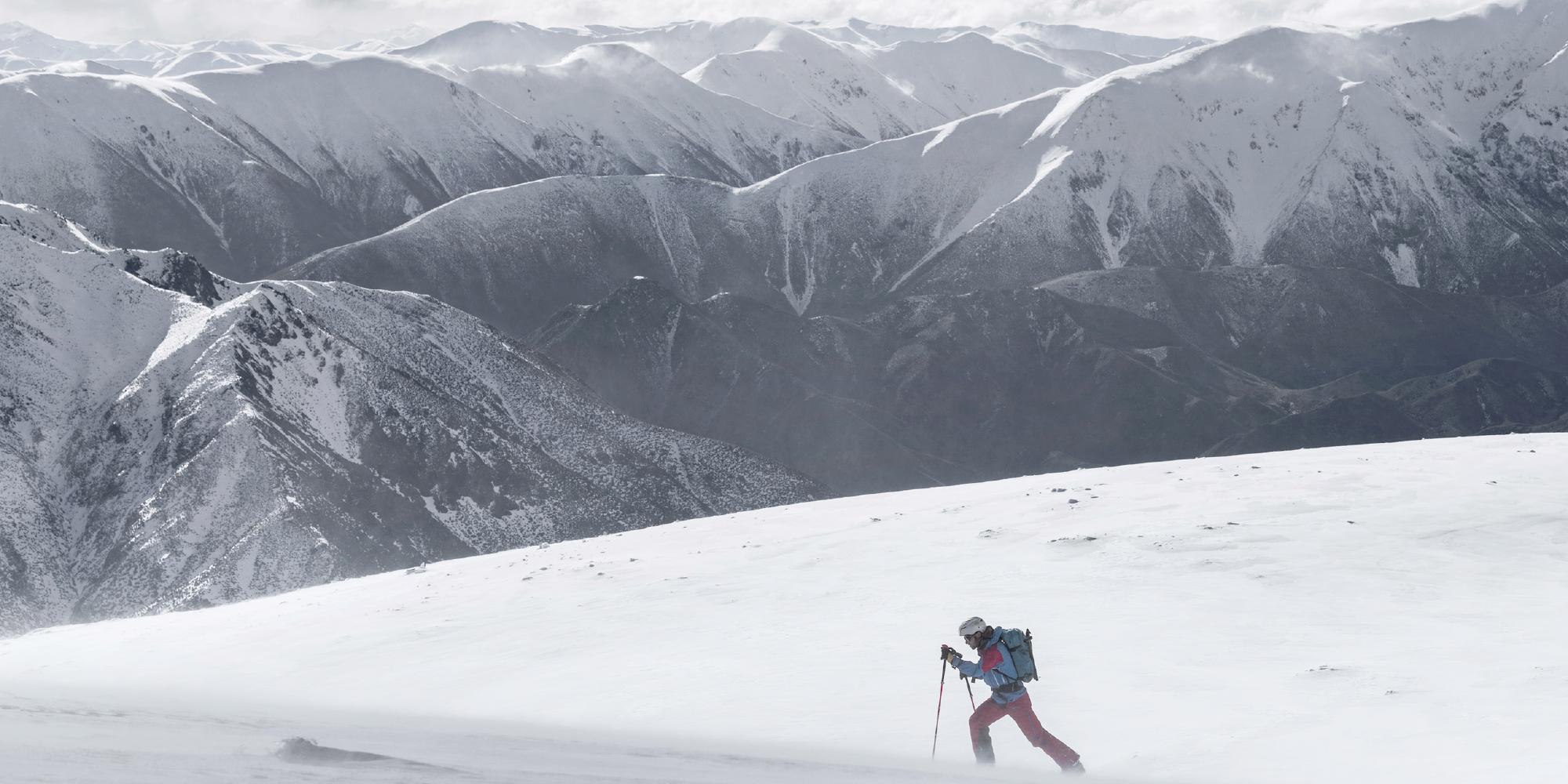 Ein Skitourengeher der entlang einer Gebirgskette wandert.