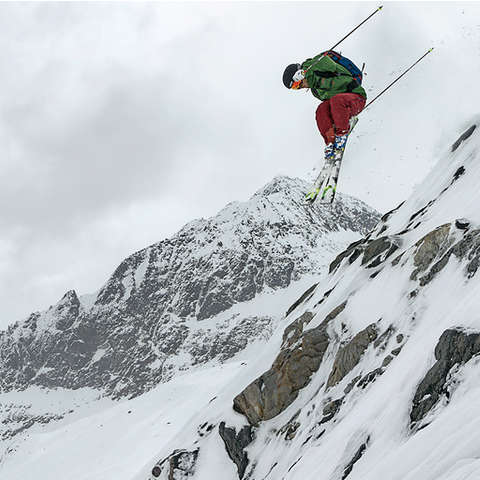Ein Freeride Skifahrer springt mit seinen Freeride Ski über einen großen Abhang