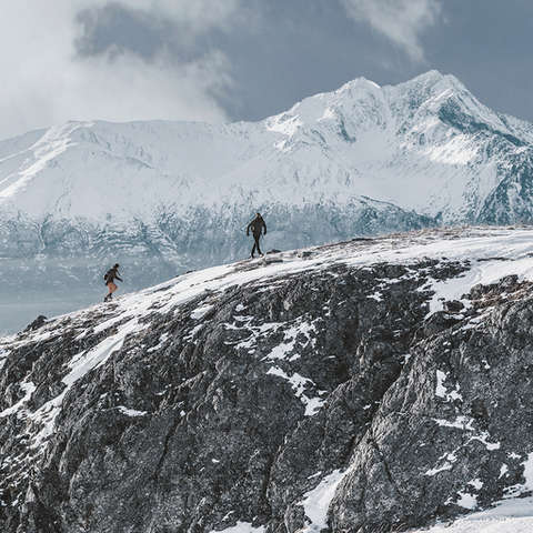 Zwei Wanderer laufen im Winter durch eine verschneite Berglandschaft