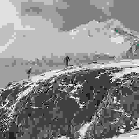 Zwei Wanderer laufen im Winter durch eine verschneite Berglandschaft