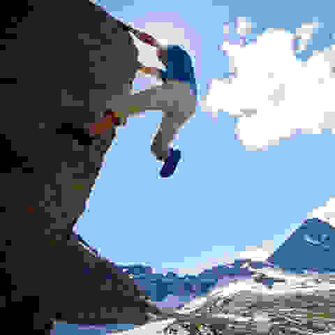 Ein mann bouldert vor einem Bergpanorama im Freien