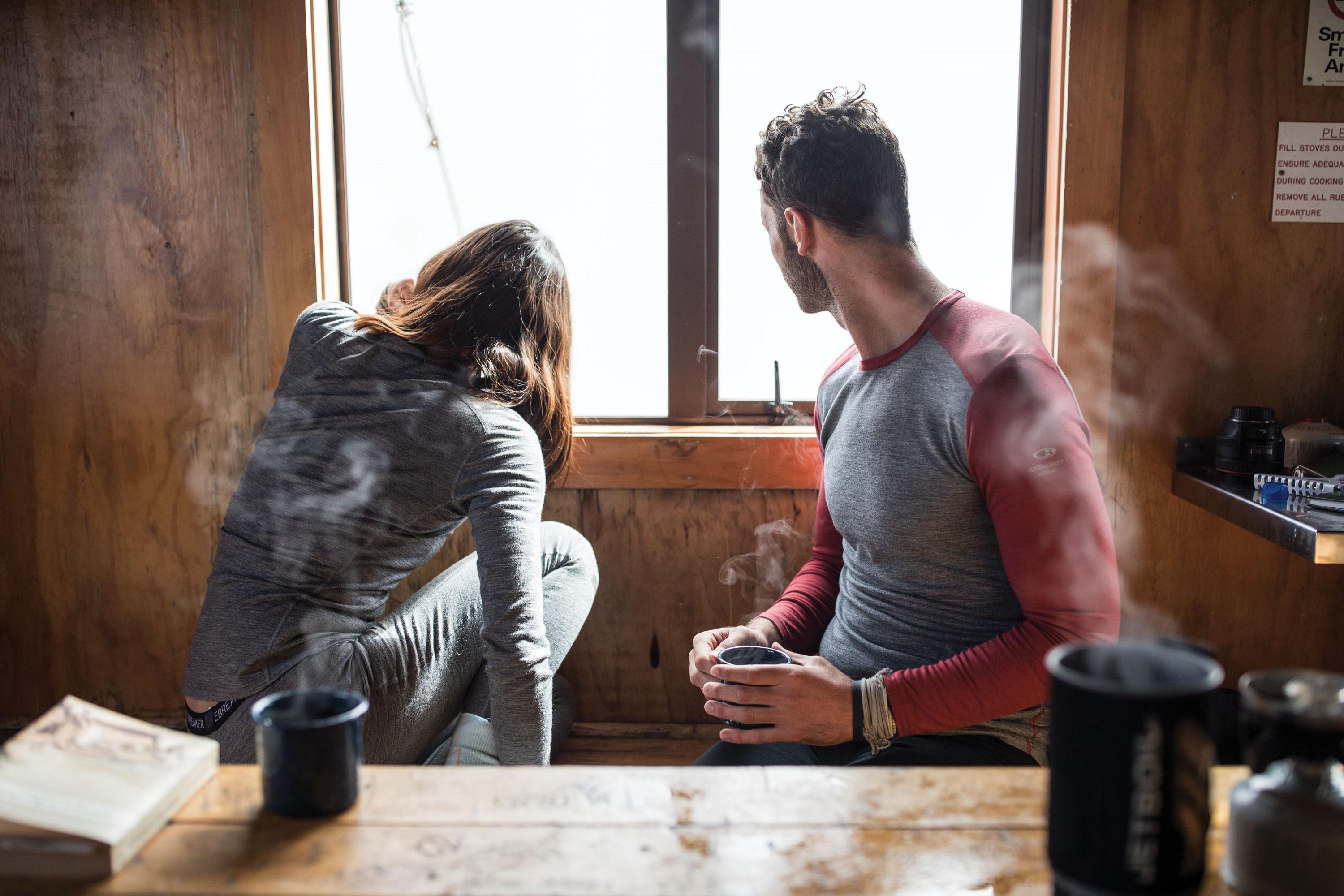 Eine Mann und ein Frau sitzen in einer Hütte und trinken heiße Getränke