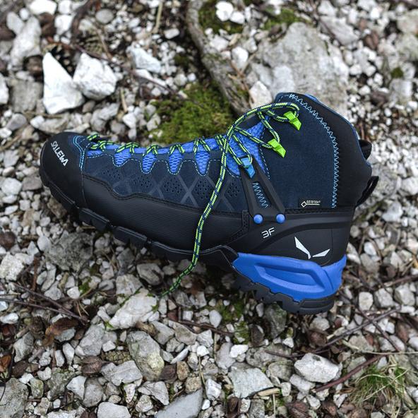 Ein Wanderer geht einen Bergweg entlang. Im Fokus sind seine Wanderschuhe. Sie sind kn&ouml;chelhoch und aus braunem Wildleder.