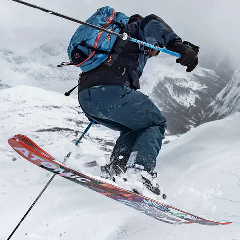 Ein Freeride Skifahrer springt mit seinen Freeride Ski über einen kleinen Abgrund
