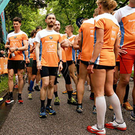 Diverse Läufer stehen vor dem Start beim Hamburg Stadtlauf in einer Gruppe zusammen.