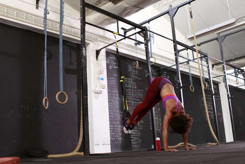 Eine Frau trainiert im Fitnessstudio mit ihrem eigenen Körpergewicht.