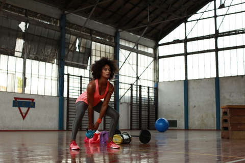 Eine Frau trainiert mit Kettlebells in einer Sporthalle.