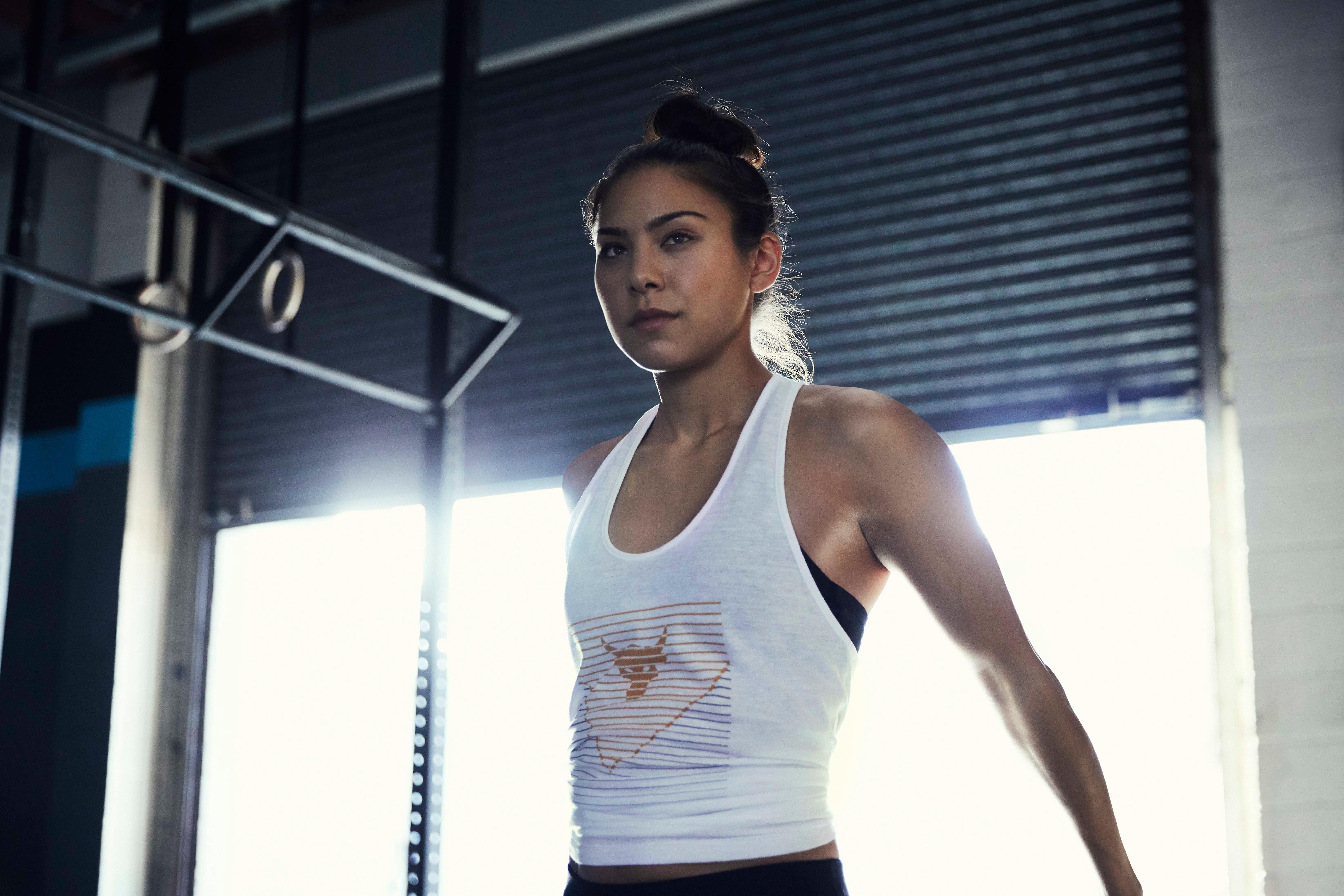 Eine Frau im weißen Sport-Top macht eine Sportübung im Fitnessstudio