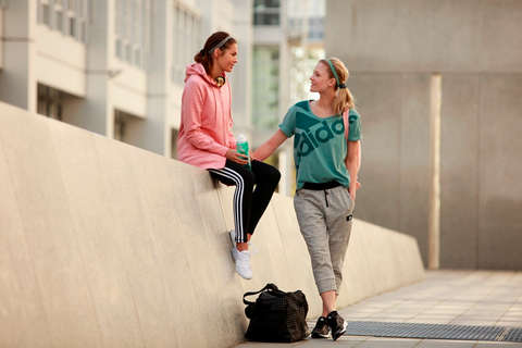 2 Frauen unterhalten sich auf der Straße. Beide tragen Trainingsoutfits.