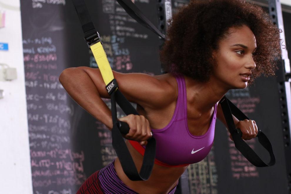 Eine Frau trainiert an einem Schlingentrainer.